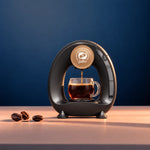 Cafetera iCafilas Mini Q preparando café americano en una taza de vidrio, sobre fondo azul