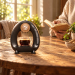 Cafetera iCafilas Mini Q con un americano en una mesa de madera, junto a una persona leyendo