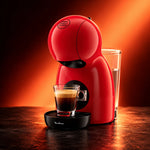 Cafetera Nescafé® Dolce Gusto® Piccolo XS roja con un espresso, con luz roja de fondo