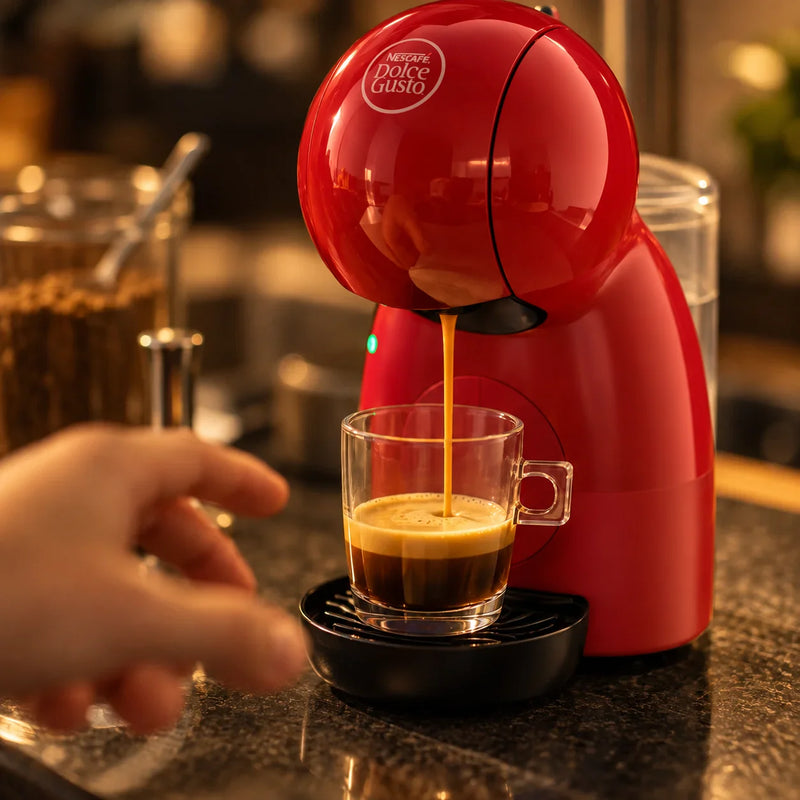 Espresso cayendo de la cafetera Nescafé® Dolce Gusto® Piccolo XS roja a una taza de vidrio