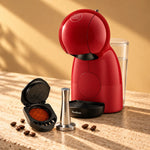 Cafetera Nescafé® Dolce Gusto® Piccolo XS roja junto a la cápsula recargable iCafilas con café y su tamper
